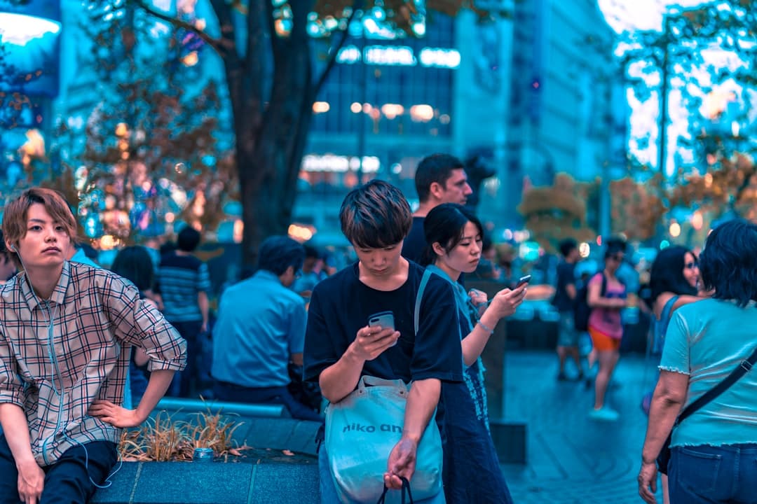 Voyageurs consultant leur smartphone dans une rue de Tokyo, Japon